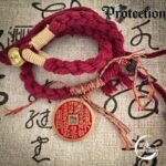 A set of protection amulets designed as a red string bracelet for the wrist. These unique protection amulets feature a detailed Mountain Spirit amulet coin for spiritual safety. Amulet of proof against detection and location, blessed by Taoist Master. Amulet protection from ghost and negative energy.